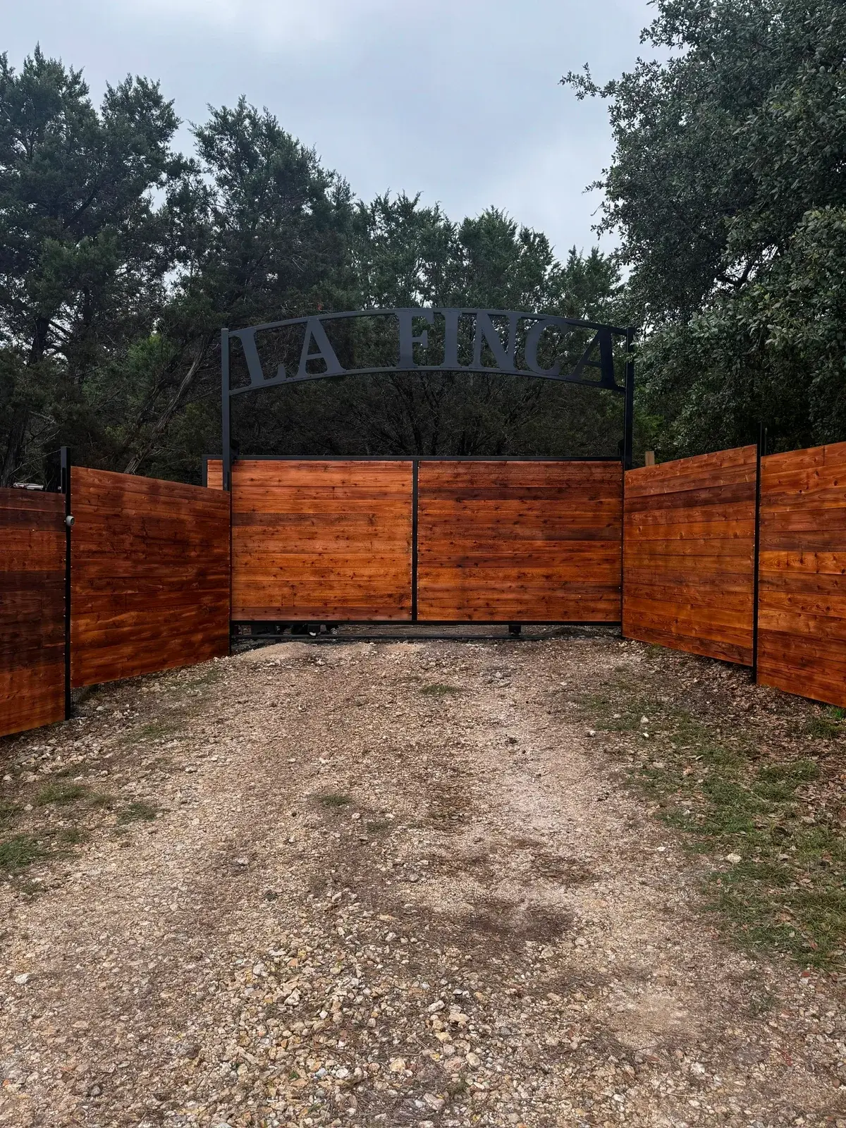 The wooden entrance gate with the metal La Finca sign arching overhead