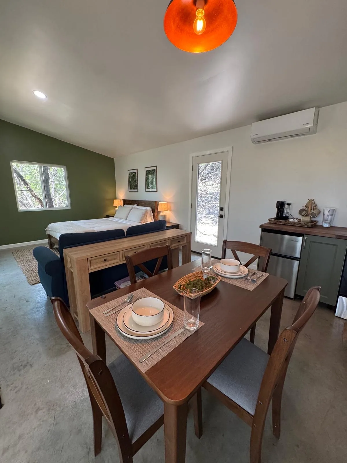 A two-seat table set with bowls and glasses, the kitchenette and bed behind it